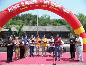 Picture of choir members performing in China in front of a banner saying Performing in Harmony with Olympic Spirit.